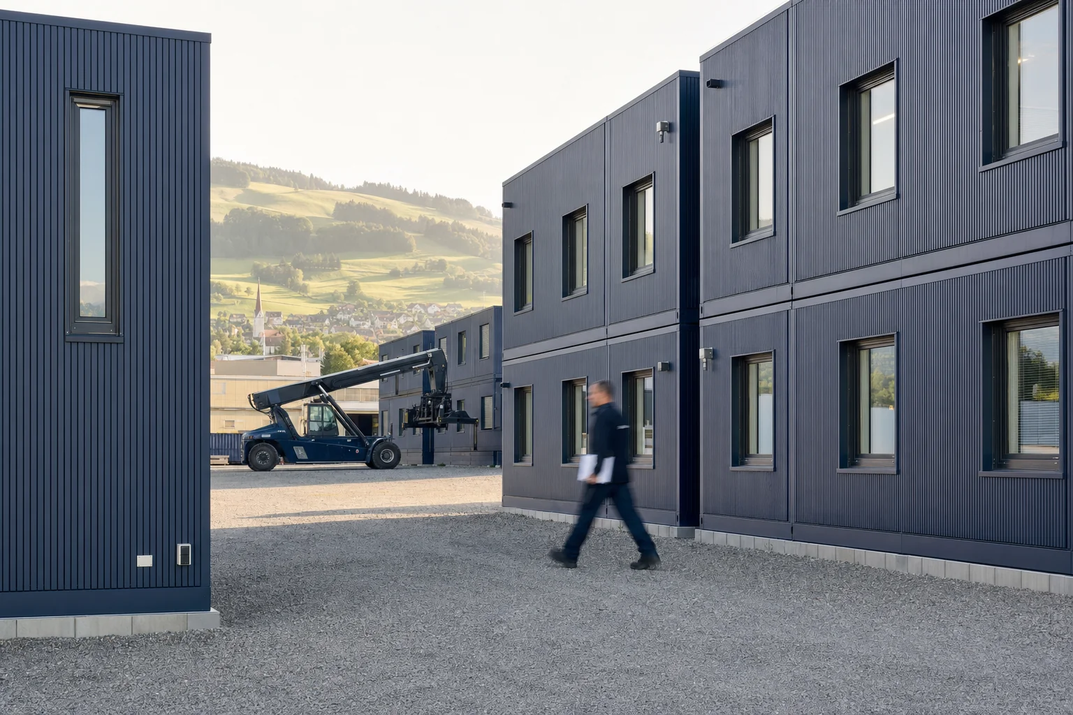 Werkareal der Mariacher Schweiz AG mit gestapelten Modulcontainern und Reachstacker