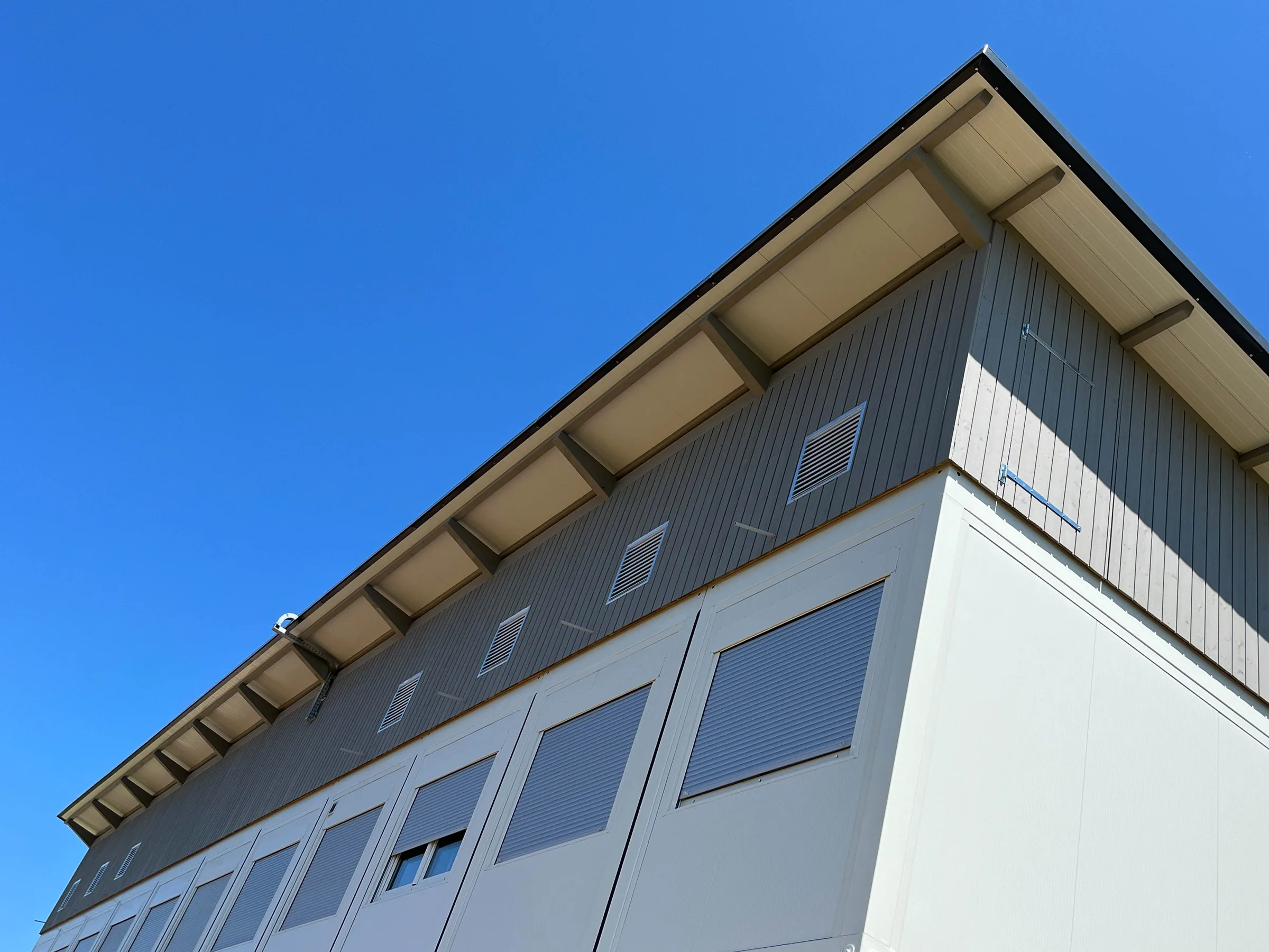 Fassade und auskragender Dachrand der Sozialunterkunft Höri aus der Untersicht
