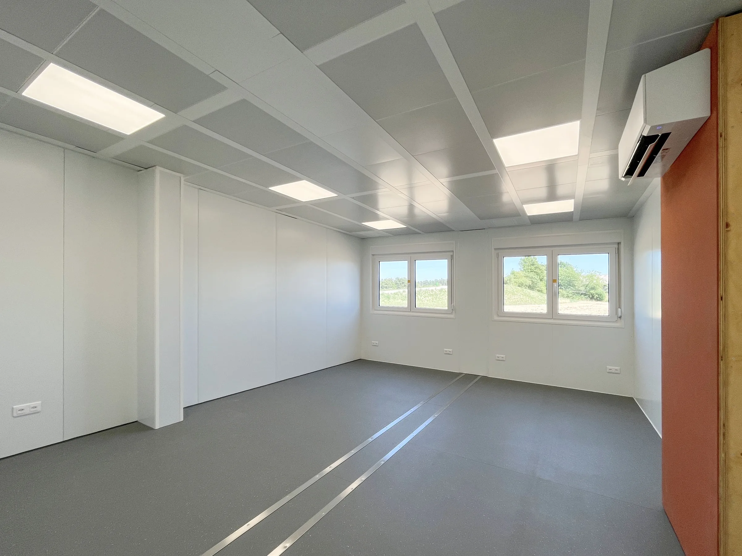 Heller Aufenthaltsraum mit Fensterband und Klimagerät in der Sozialunterkunft Höri