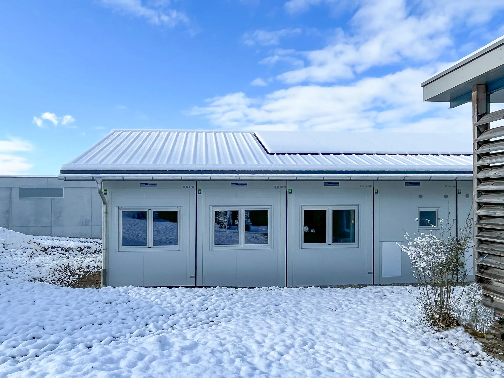 Längsfassade der Sozialunterkunft Winkel mit Fensterreihe und Photovoltaikdach