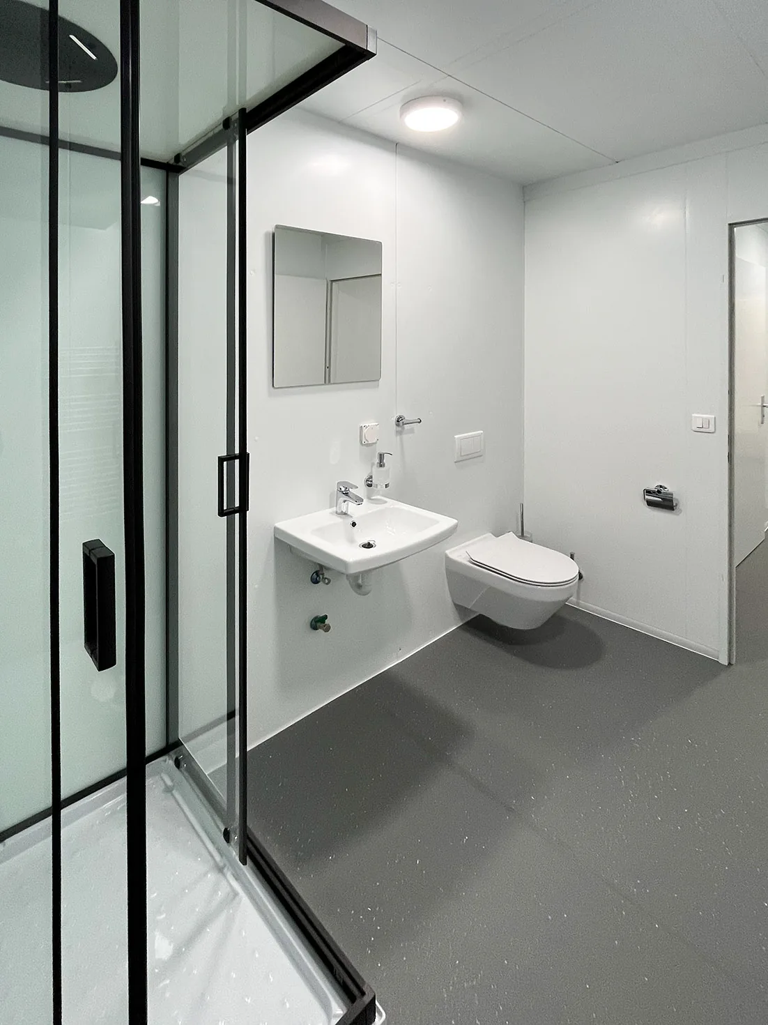 Sanitärbereich mit Waschbecken, WC und Duschkabine in der Sozialunterkunft Winkel