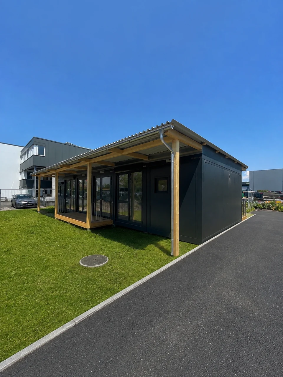 Kindertagesstätte Basel in Modulbauweise mit überdachter Holzterrasse auf der Rasenfläche